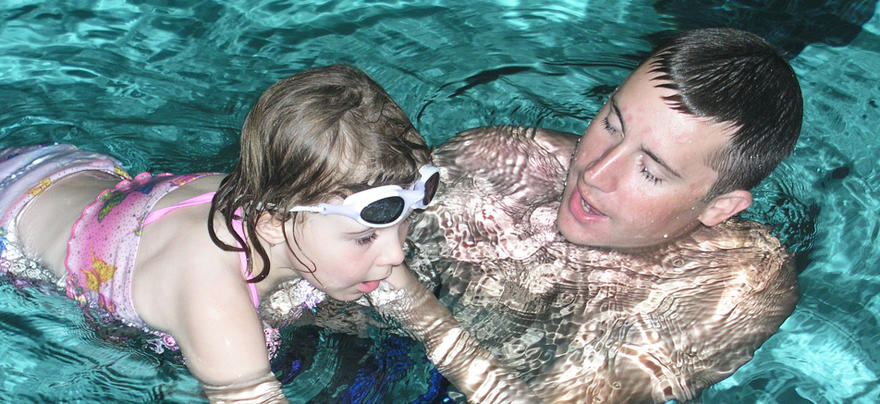 Instructor helping a young girl learn how to swim 