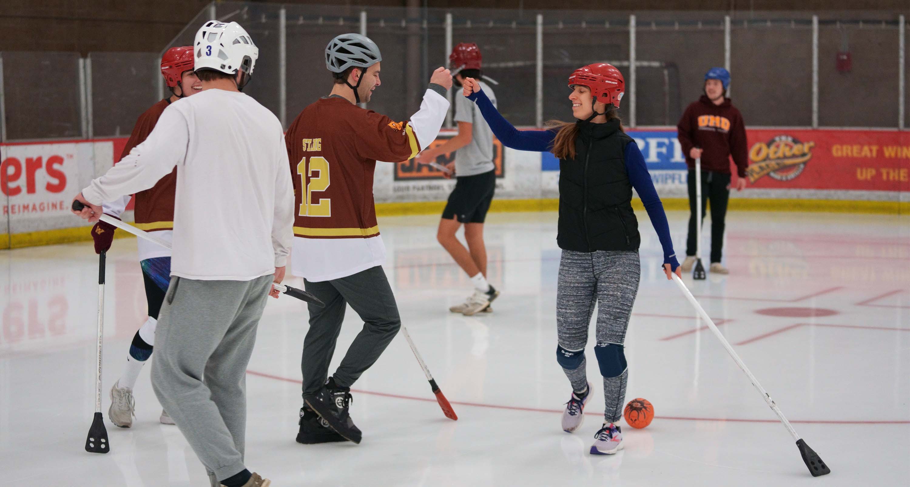 students playing broomball and fist bumping