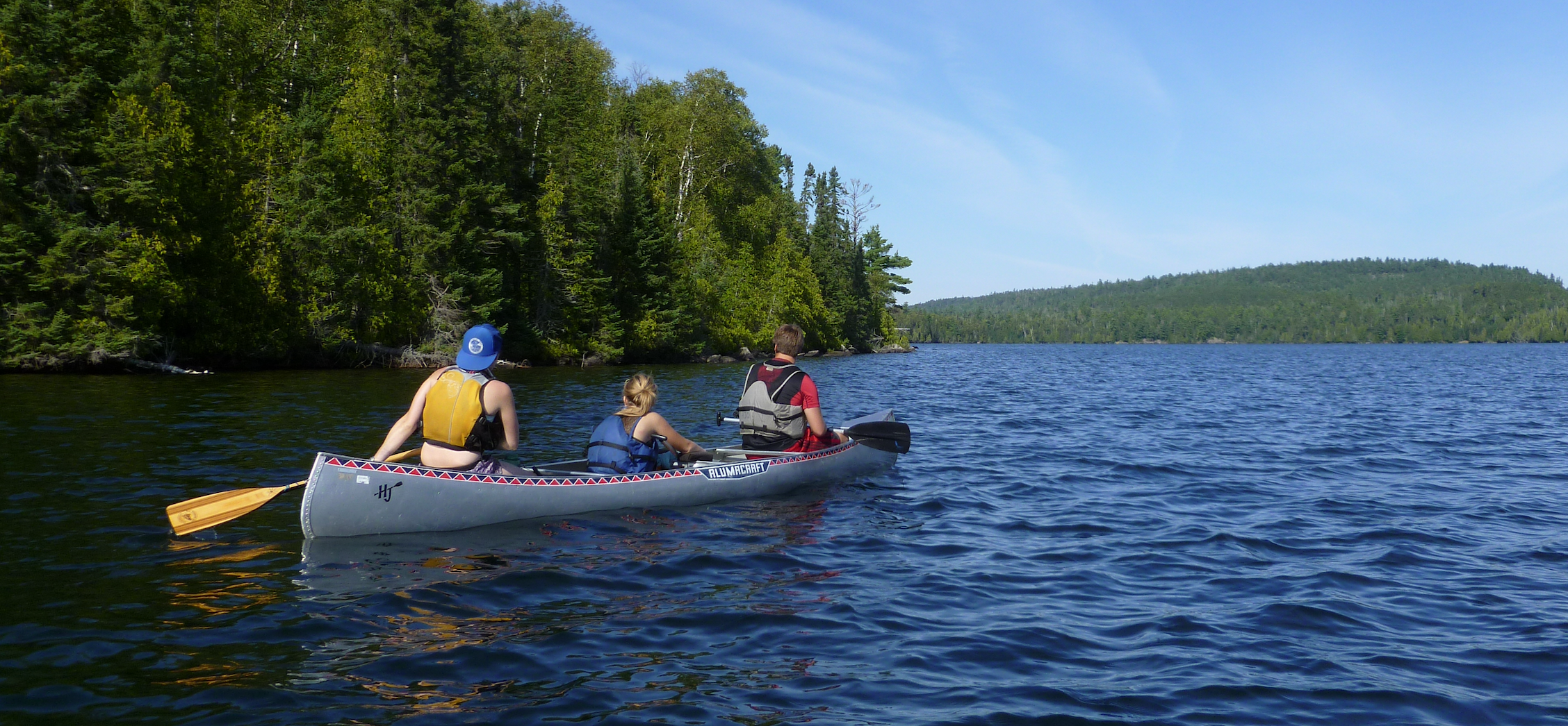 three people paddling a canoe in the Boundat Waters
